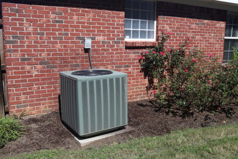 outdoor hvac unit sitting in an area with the surrounding things are cleared out of the way for safety