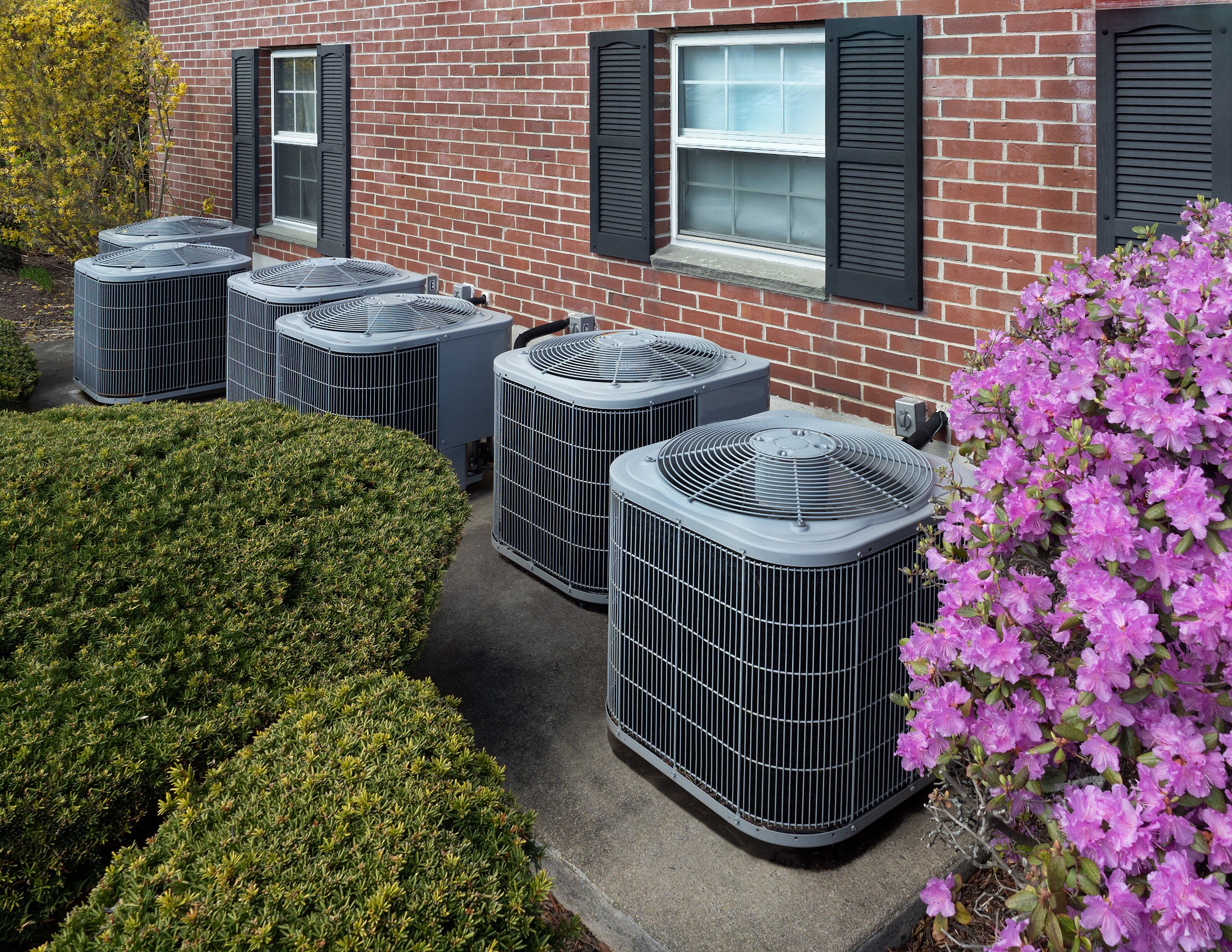 a line of outdoor ac units outside of an apartment building