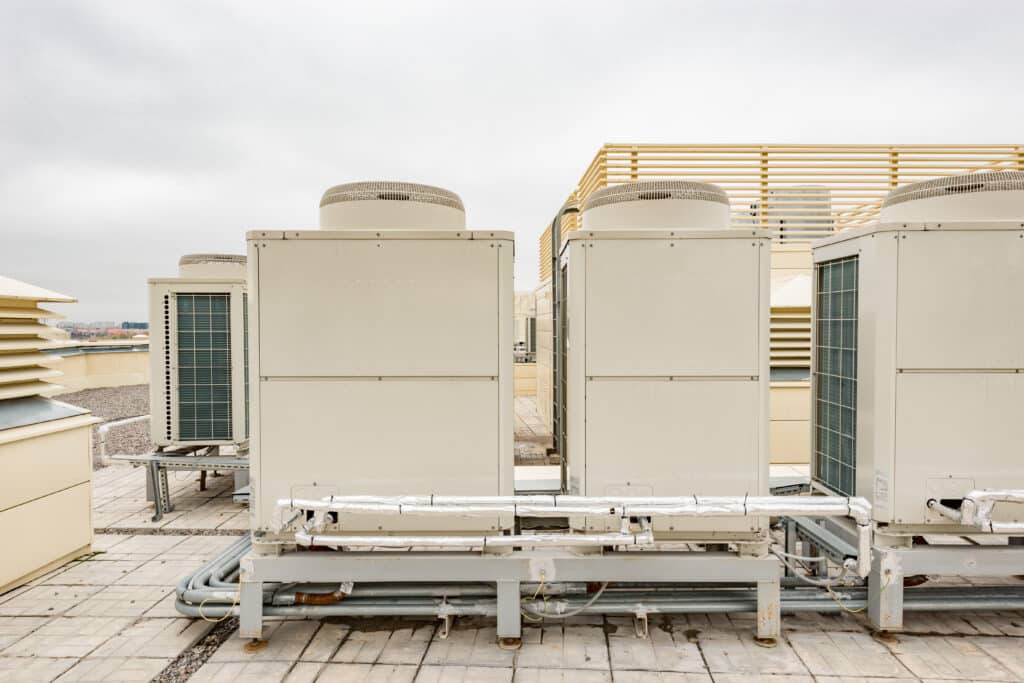 line of commercial ac units positioned on the top of a commercial building. about 4 units installed