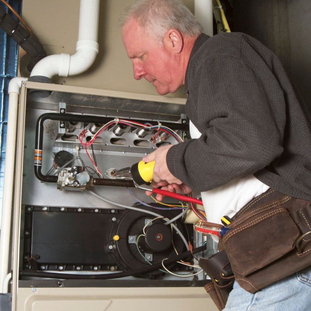closeup of an hvac technician performing repairs on a furnace