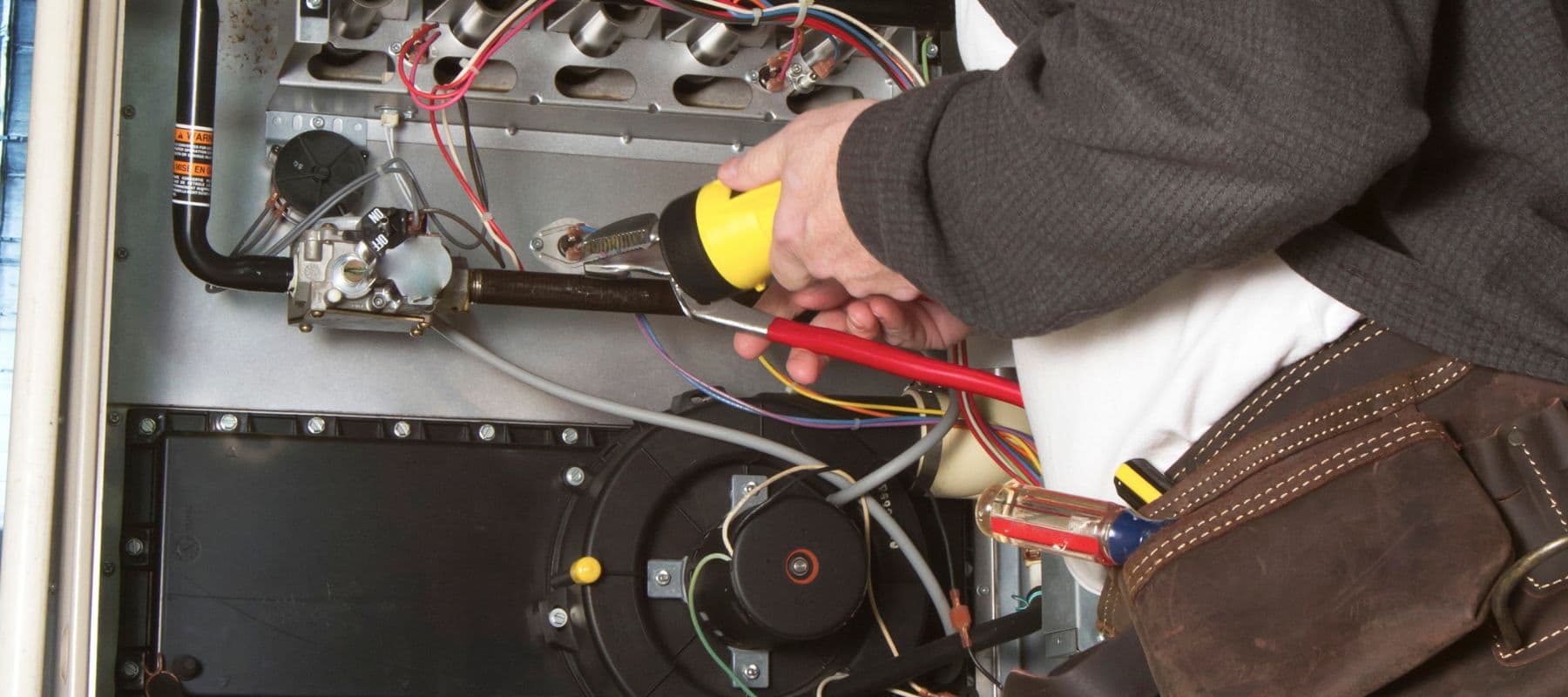 closeup of an hvac technician performing repairs on a furnace