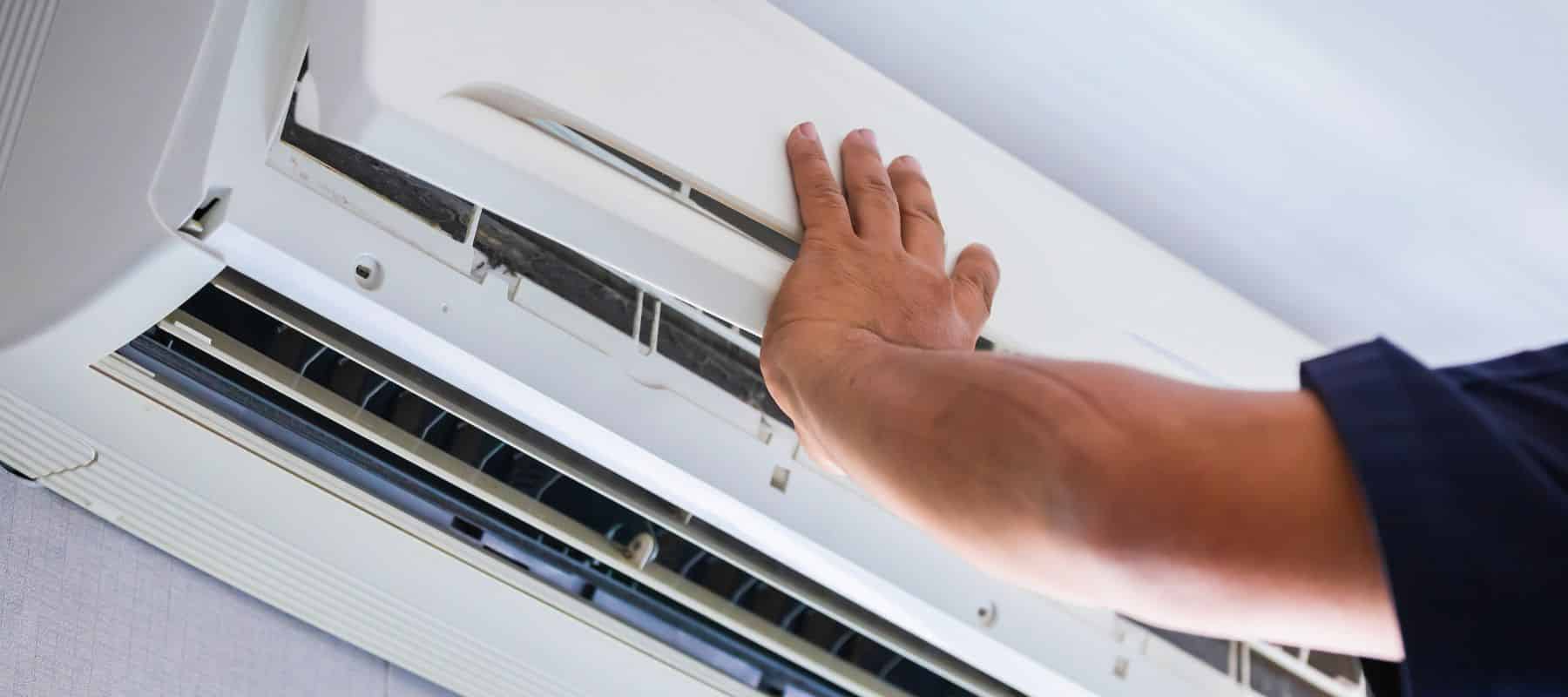 close up of a man working on a ductless ac unit