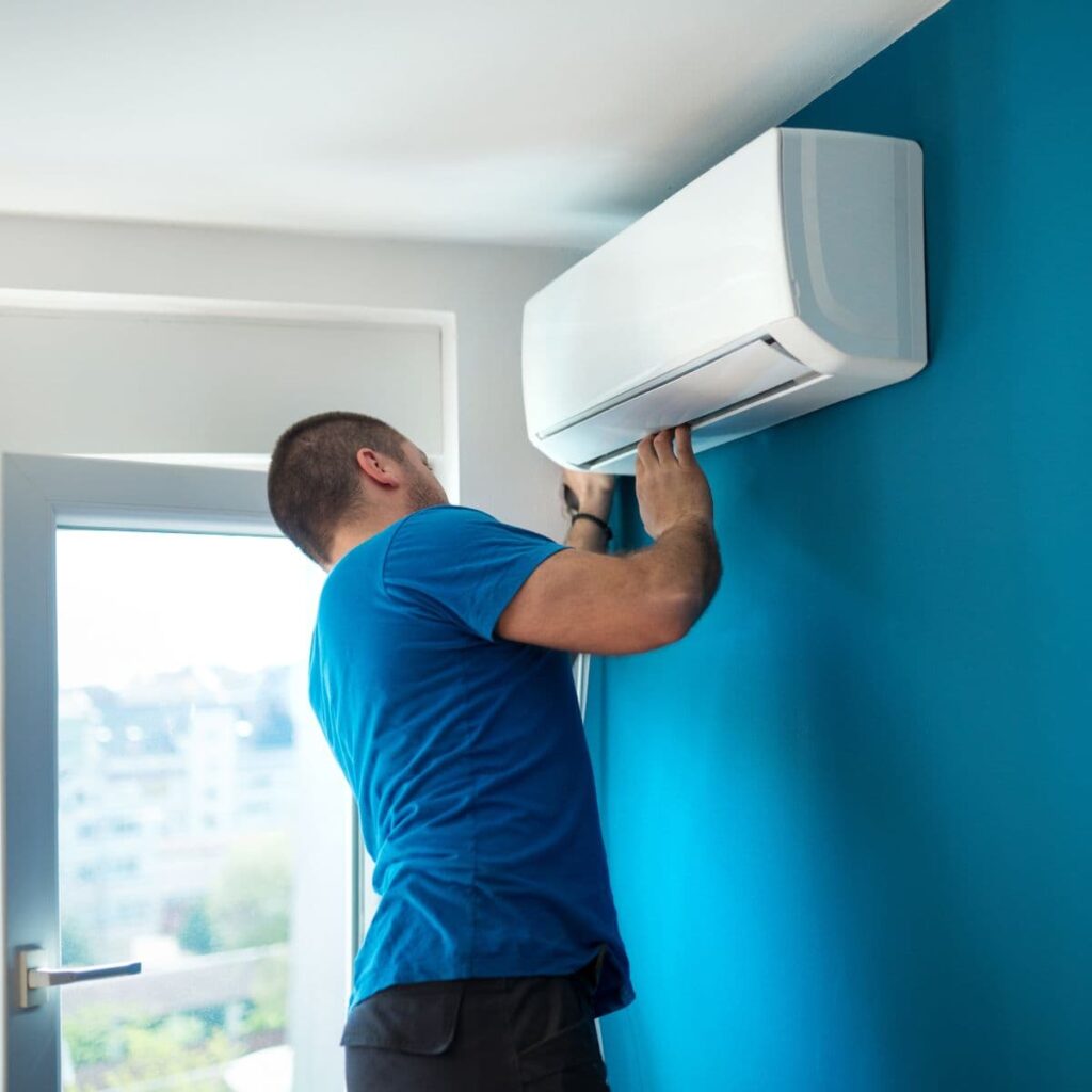 hvac technician looking thoroughly at a newly installed ductless ac unit that was installed on a blue wall