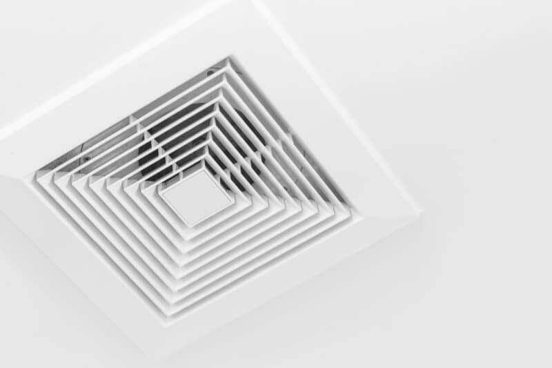 closeup of a white square air duct vent on a white ceiling