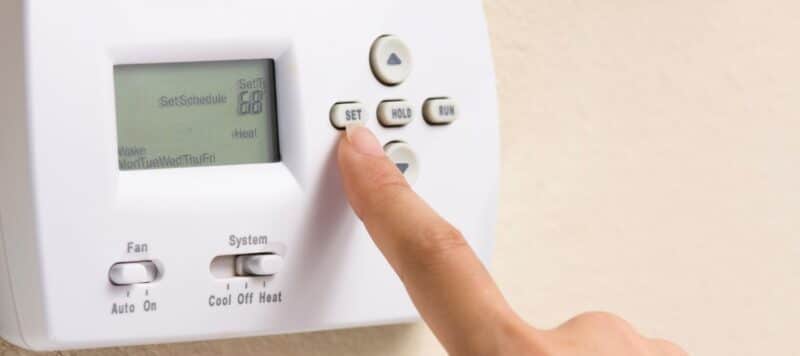 person setting their thermostat to the proper settins