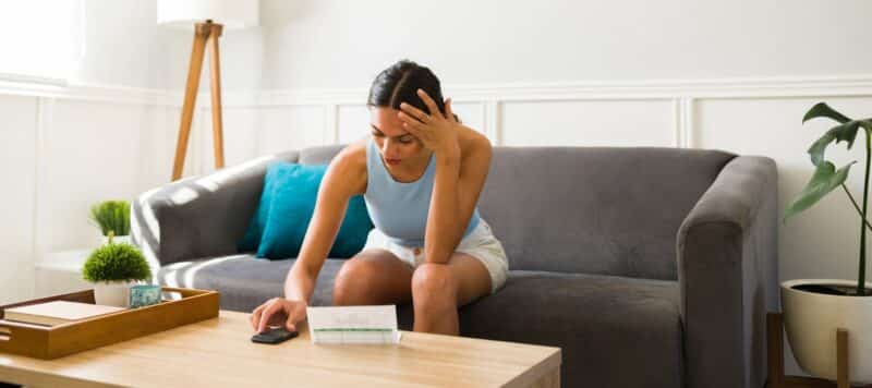 woman sitting on her couch feeling the heat from a unmaintained air conditioner