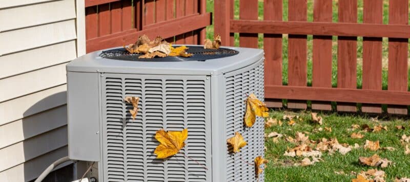 outdoor hvac unit that has leaves all on the system during the fall season
