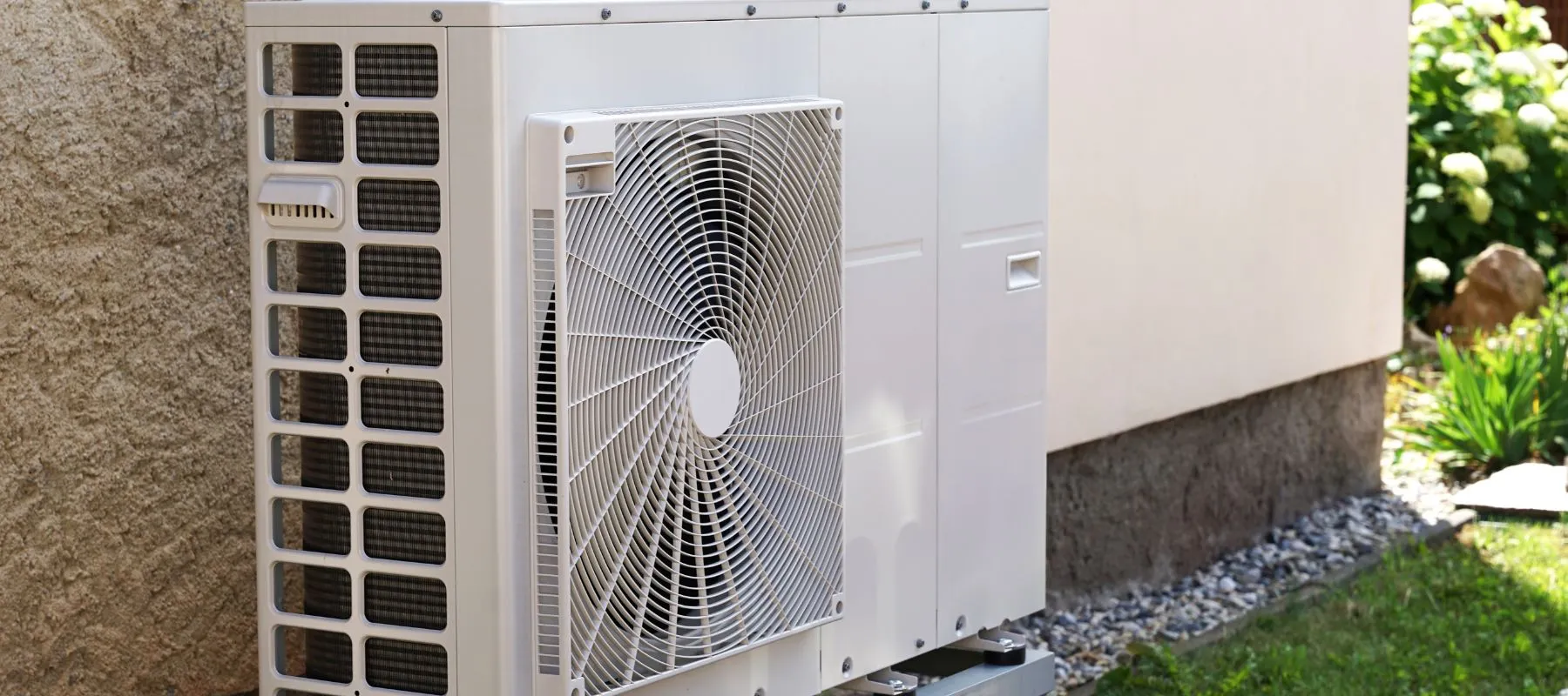 Outdoor heat pump unit installed beside a house exterior wall